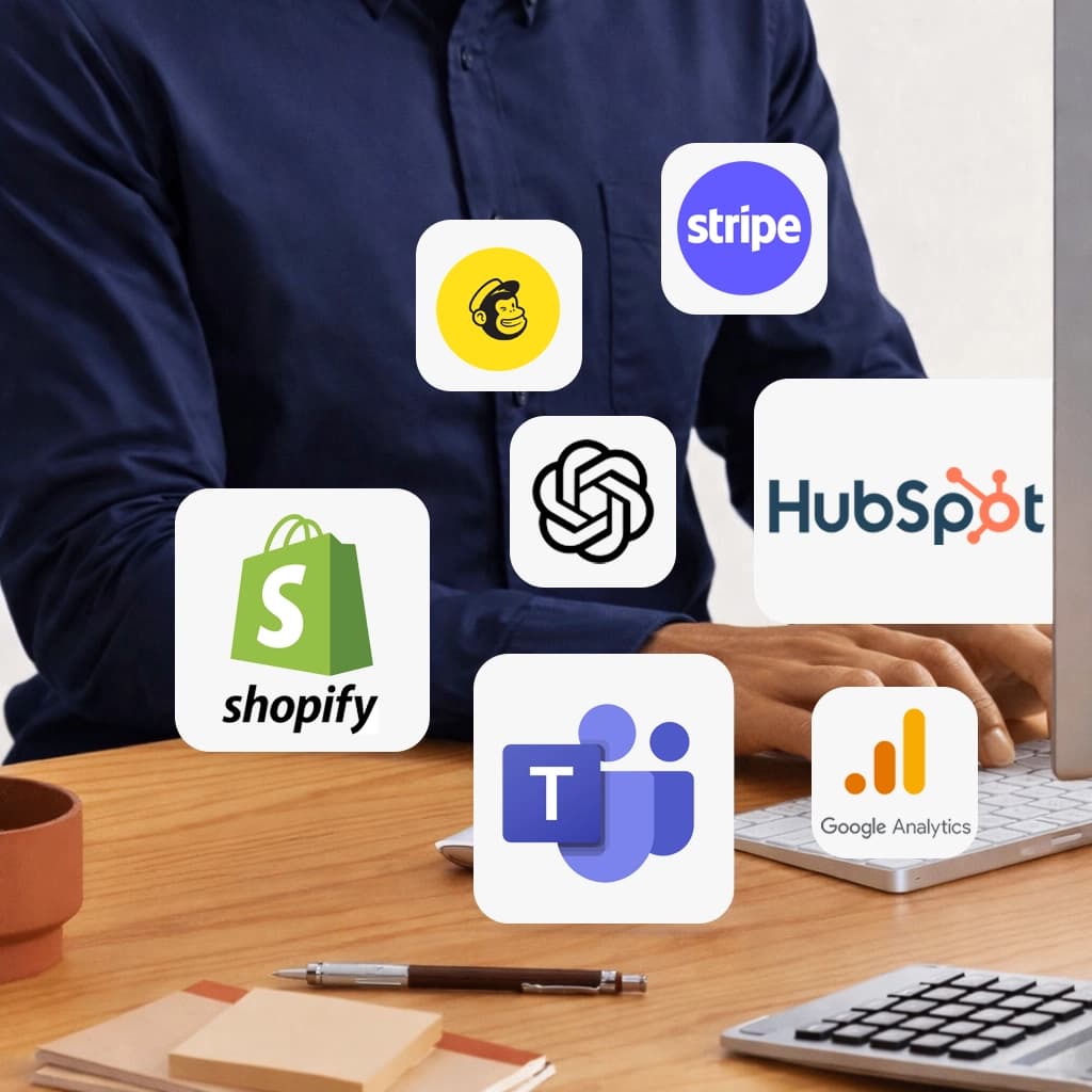 Man sitting at a desk working on a laptop with various integration icons floating around him